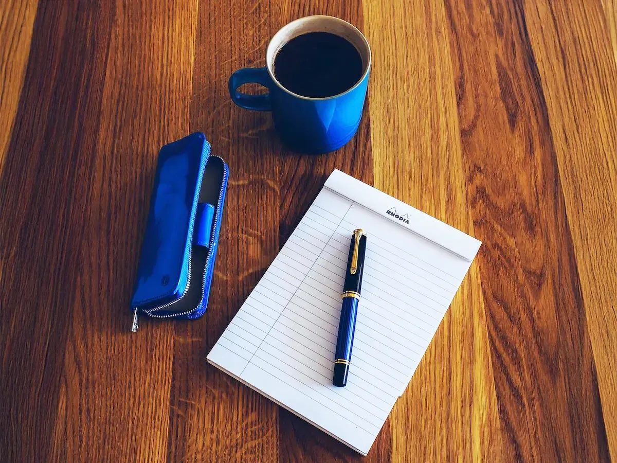 Plniace oero, peračník, poznámkový blok a káva